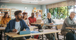 Des stagiaires en classe, utilisant des ordinateurs portables et prenant des notes dans des cahiers.